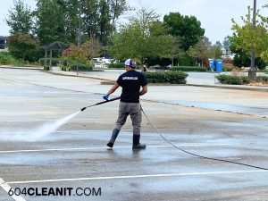 The image of the man using a power washer.